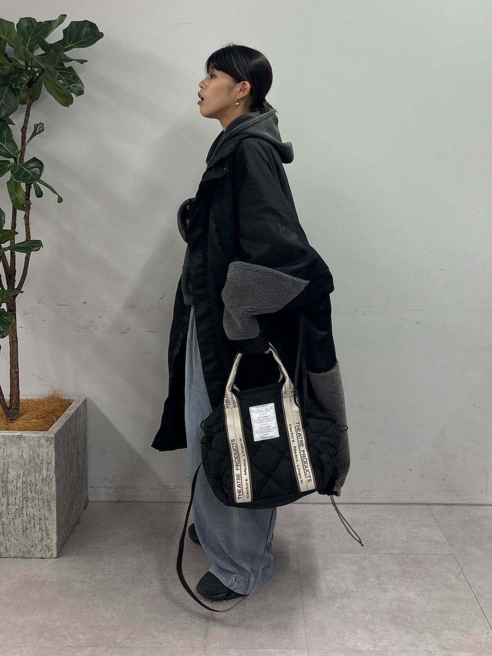 グレー系のパーカー、ブラック系のモッズコート、ブルー系のデニムパンツを着用したレディースの秋コーディネートの2枚目の写真