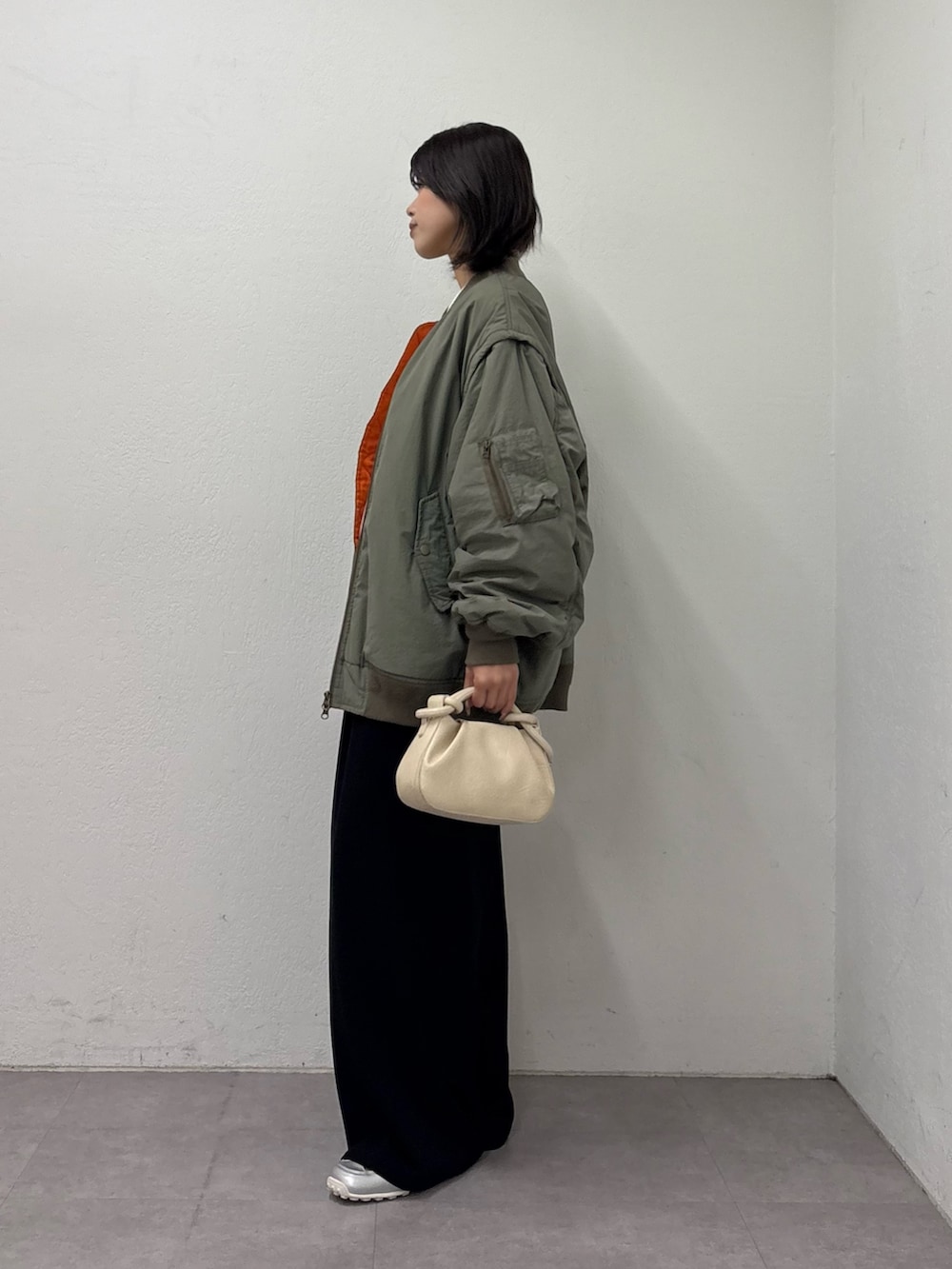 グリーン系のMA-1、ホワイト系のニット/セーター、ベージュ系のショルダーバッグを着用したレディースの冬コーディネートの2枚目の写真