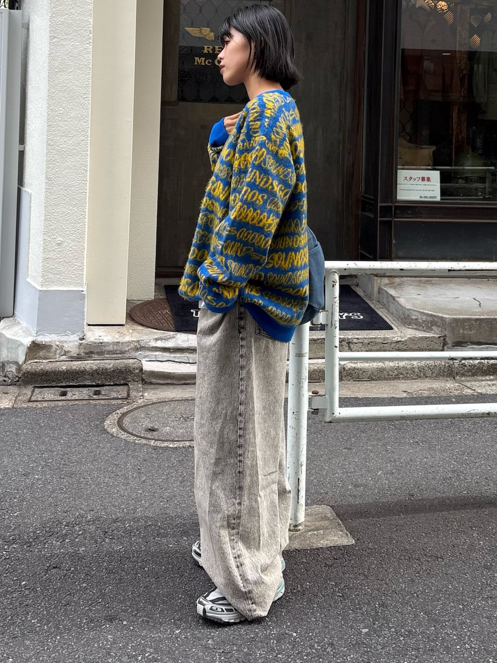 イエロー系のニット/セーター、ブラック系のデニムパンツ、ブルー系のトートバッグを着用したレディースの秋コーディネートの2枚目の写真