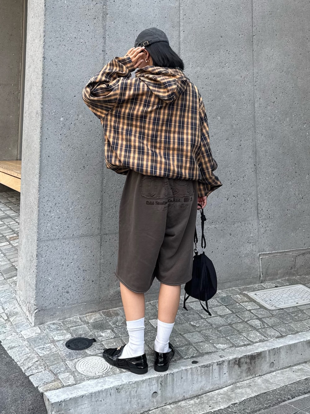 イエロー系のブルゾン、ブラウン系のスウェットパンツ、ブラック系のショルダーバッグを着用したレディースの夏コーディネートの4枚目の写真