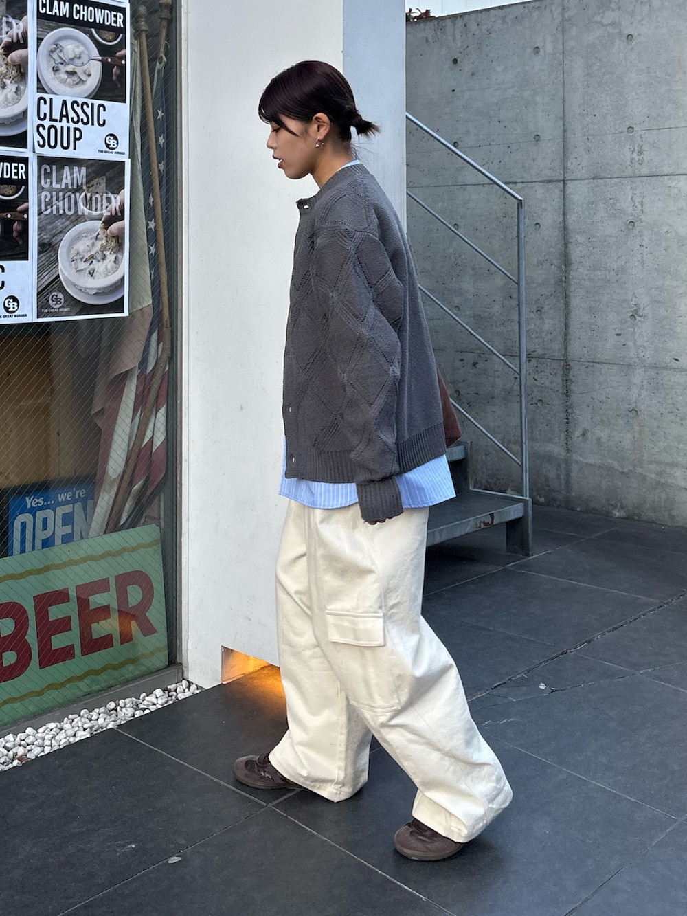 グレー系のカーディガン/ボレロ、ホワイト系のデニムパンツ、ブラウン系のトートバッグを着用したレディースの冬コーディネートの2枚目の写真