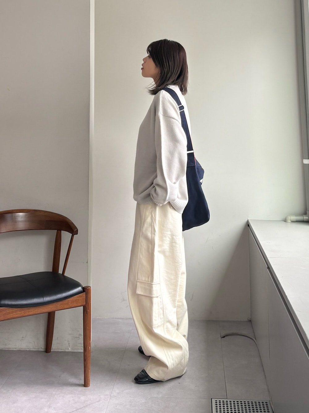 グレー系のニット/セーター、ホワイト系のカーゴパンツ、ブルー系のショルダーバッグを着用したレディースの春コーディネートの3枚目の写真