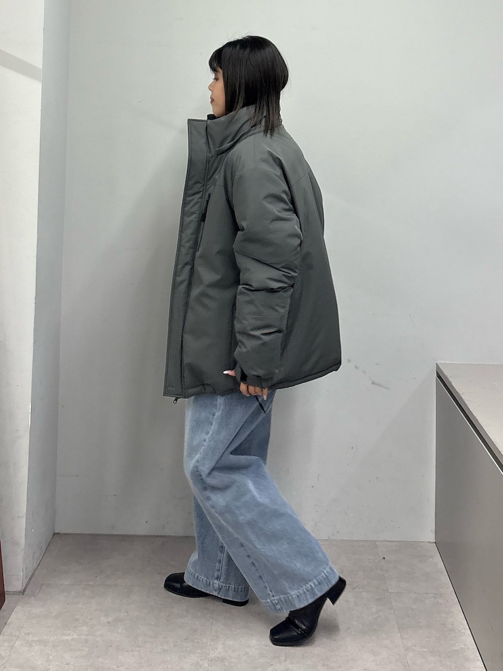 グレー系のダウンジャケット/コート、ブラック系のニット/セーター、ブルー系のデニムパンツを着用したレディースの冬コーディネートの2枚目の写真