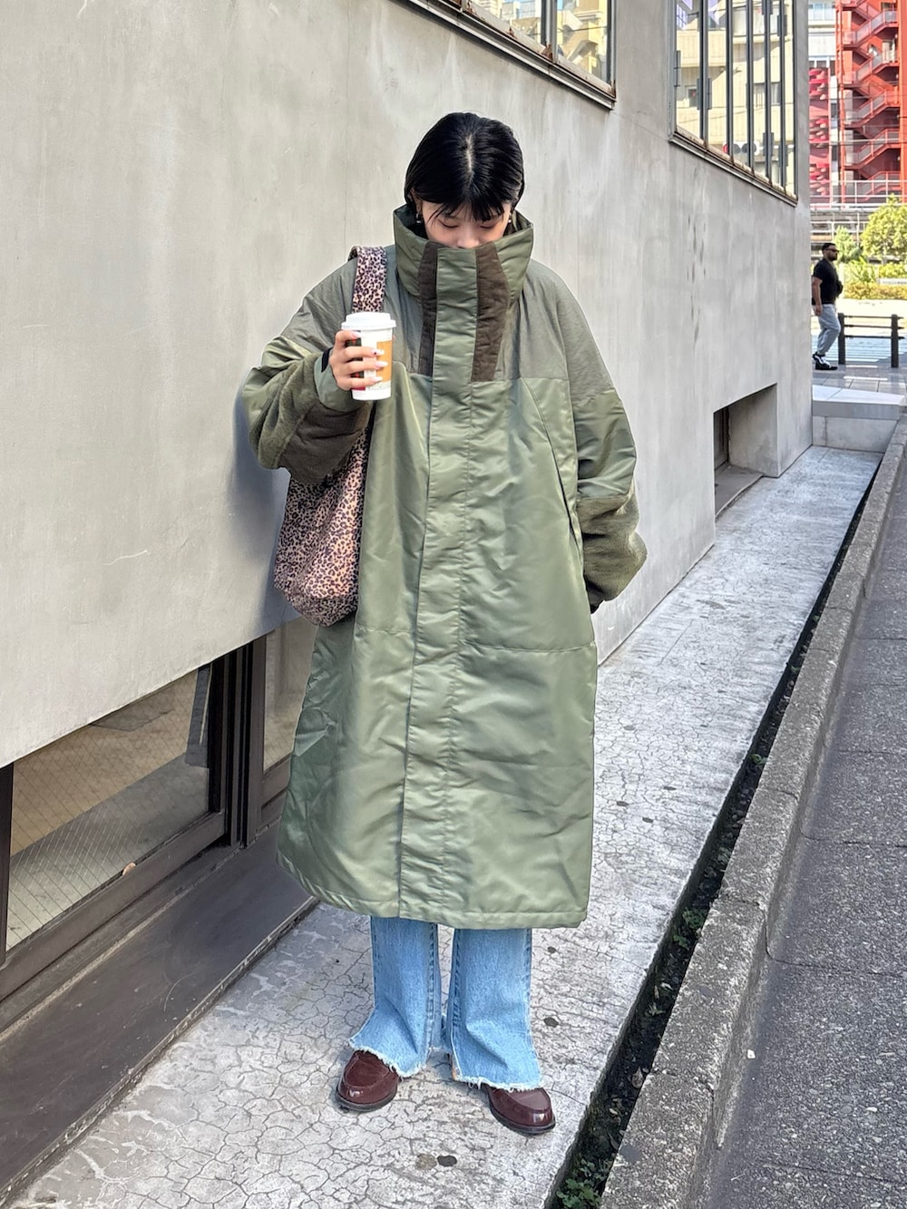 グリーン系のモッズコート、ブルー系のデニムパンツ、ベージュ系のトートバッグを着用したレディースの秋コーディネートの2枚目の写真