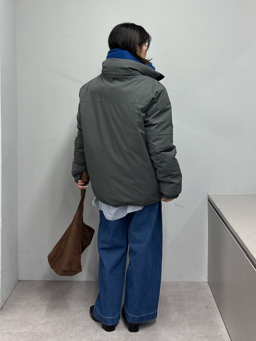 グレー系のダウンジャケット/コート、ブラック系のブーツ、ブルー系のデニムパンツを着用したレディースの冬コーディネートの3枚目の写真