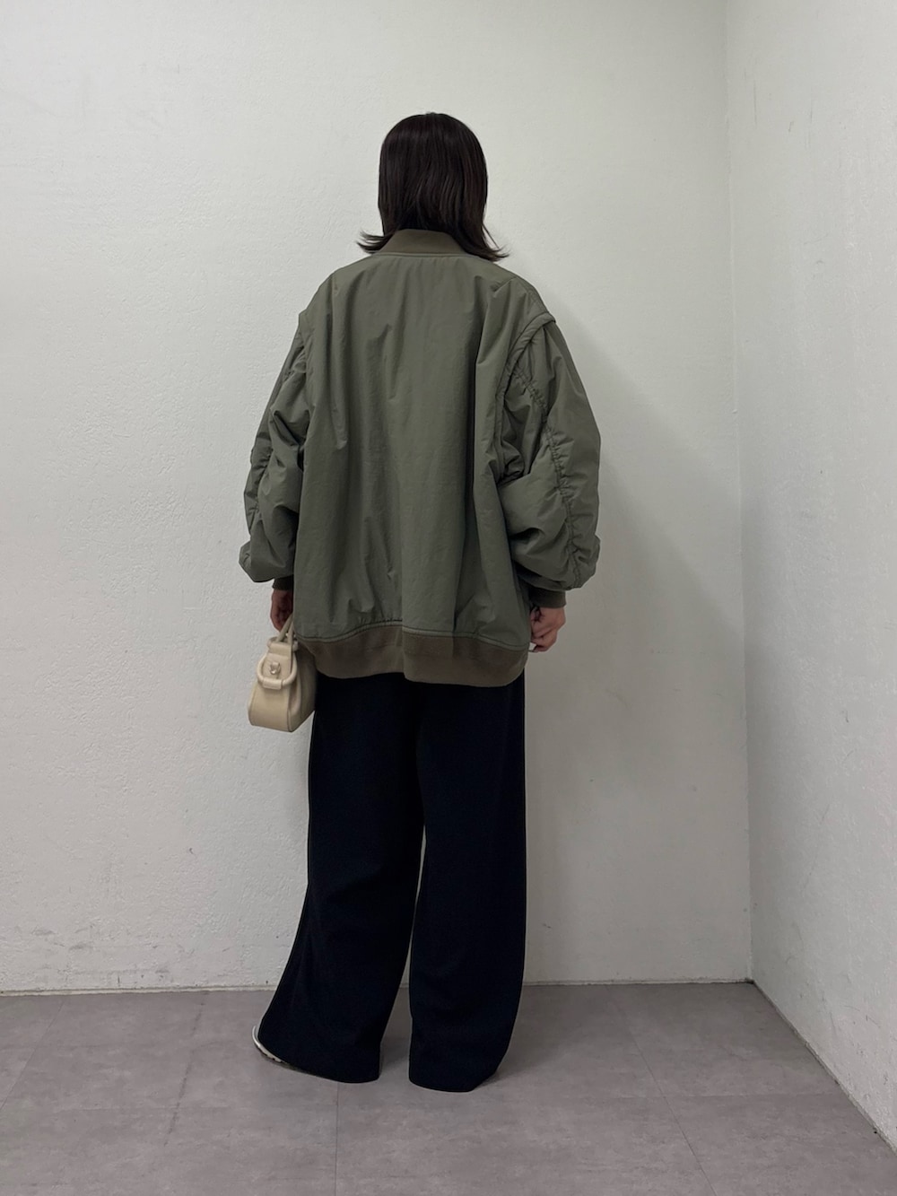 グリーン系のMA-1、ホワイト系のニット/セーター、ベージュ系のショルダーバッグを着用したレディースの冬コーディネートの3枚目の写真