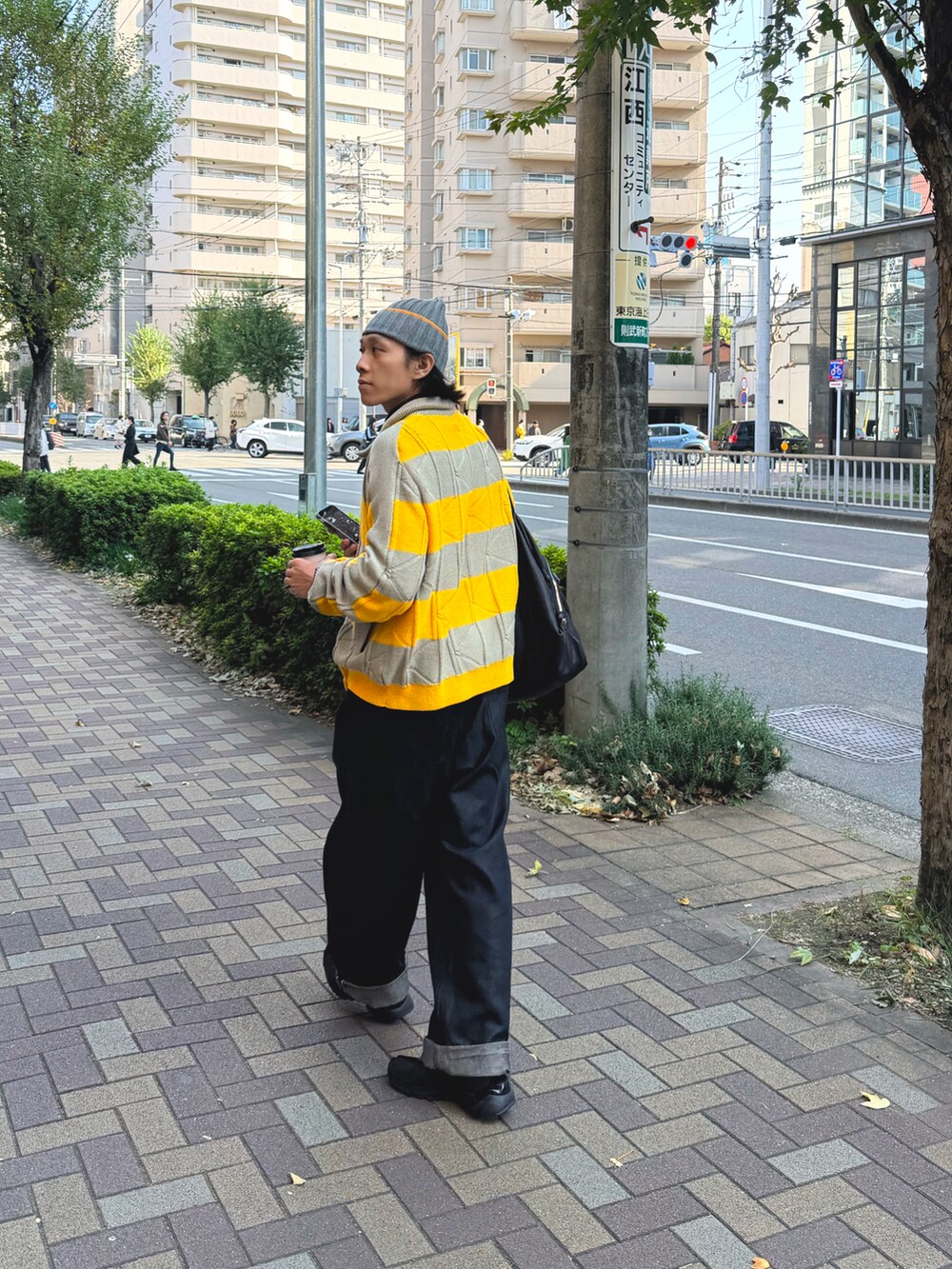 イエロー系のニット/セーター、ブラック系のデニムパンツ、ブラック系のスニーカーを着用したメンズの秋コーディネートの3枚目の写真