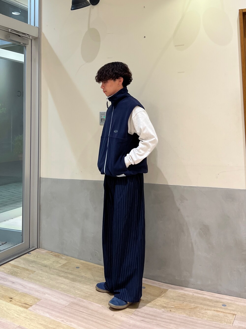 ホワイト系のTシャツ/カットソー、ブルー系のベスト、ブルー系のスラックスを着用したメンズの秋コーディネートの2枚目の写真