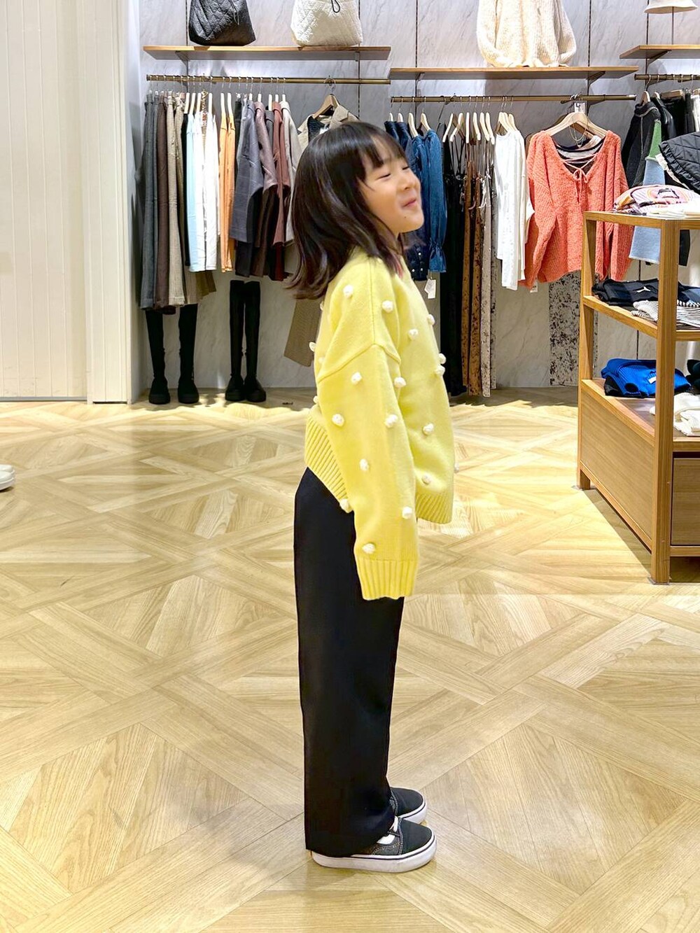 イエロー系のニット/セーター、ブルー系のチノパンツを着用したキッズの秋コーディネートの3枚目の写真