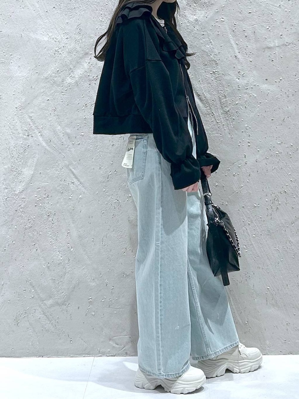 ブルー系のデニムパンツ、ブラック系のショルダーバッグ、ブラック系のスウェットを着用したレディースの冬コーディネートの4枚目の写真