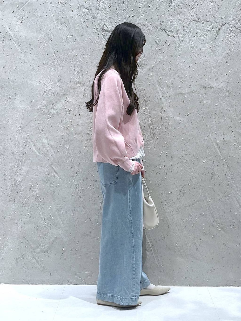 ホワイト系のショルダーバッグ、ブルー系のデニムパンツ、ホワイト系のパンプスを着用したレディースの春コーディネートの2枚目の写真