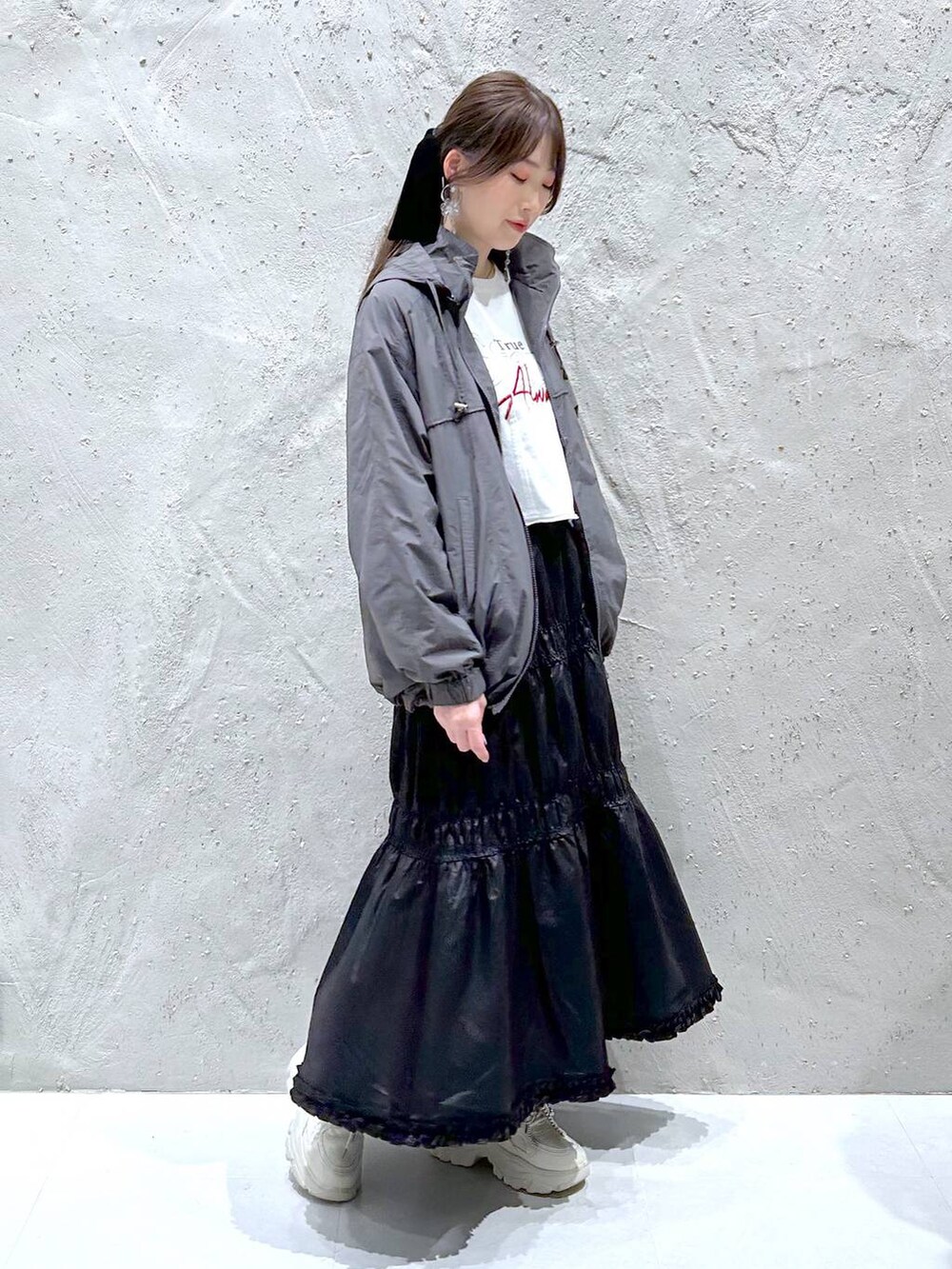 ブラック系のスカート、ホワイト系のスニーカー、ホワイト系のTシャツ/カットソーを着用したレディースの秋コーディネートの2枚目の写真