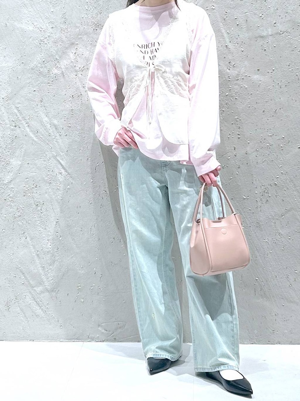 ピンク系のショルダーバッグ、ブラック系のパンプス、ブルー系のデニムパンツを着用したレディースの春コーディネートの3枚目の写真