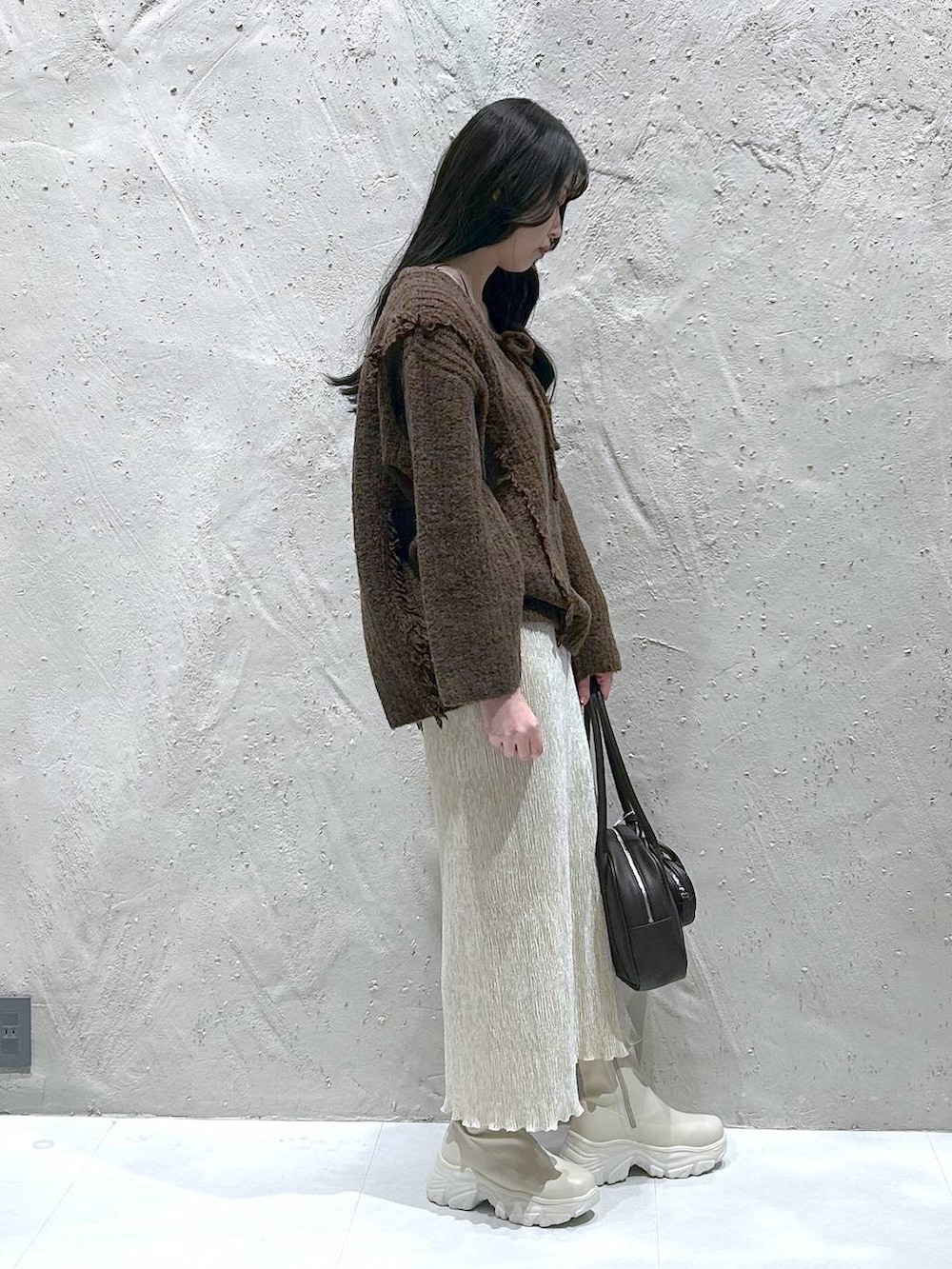 ブラウン系のニット/セーター、ホワイト系のブーツ、ホワイト系のスカートを着用したレディースの冬コーディネートの2枚目の写真
