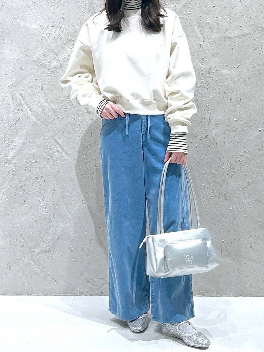 シルバー系のバレエシューズ、シルバー系のショルダーバッグ、ホワイト系のスウェットを着用したレディースの冬コーディネートの2枚目の写真