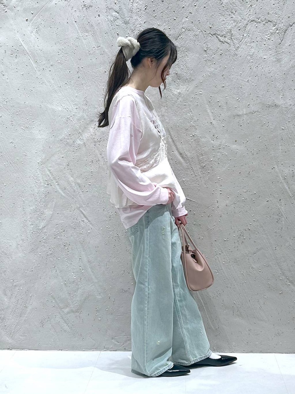 ピンク系のショルダーバッグ、ブラック系のパンプス、ブルー系のデニムパンツを着用したレディースの春コーディネートの2枚目の写真