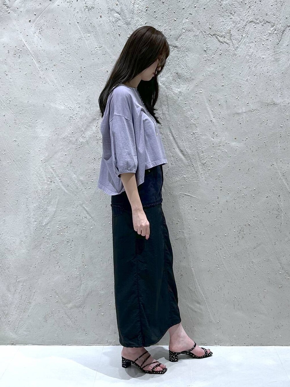 ブラック系のデニムスカート、ブラック系のサンダル、パープル系のTシャツ/カットソーを着用したレディースの夏コーディネートの3枚目の写真