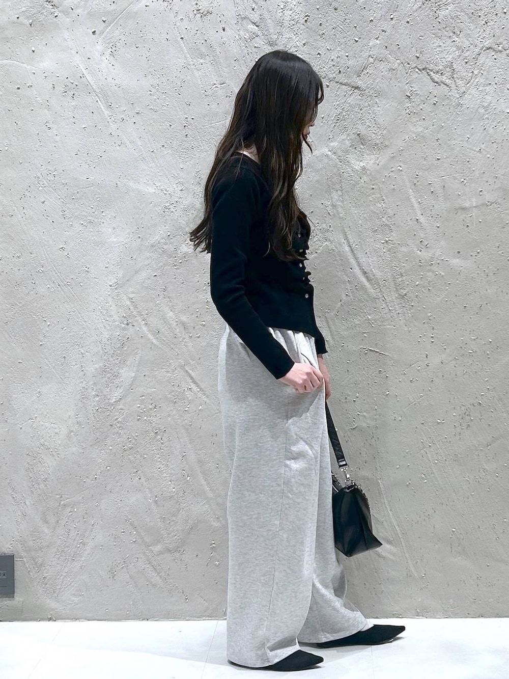 グレー系のスウェットパンツ、ブラック系のショルダーバッグ、ブラック系のパンプスを着用したレディースの春コーディネートの2枚目の写真