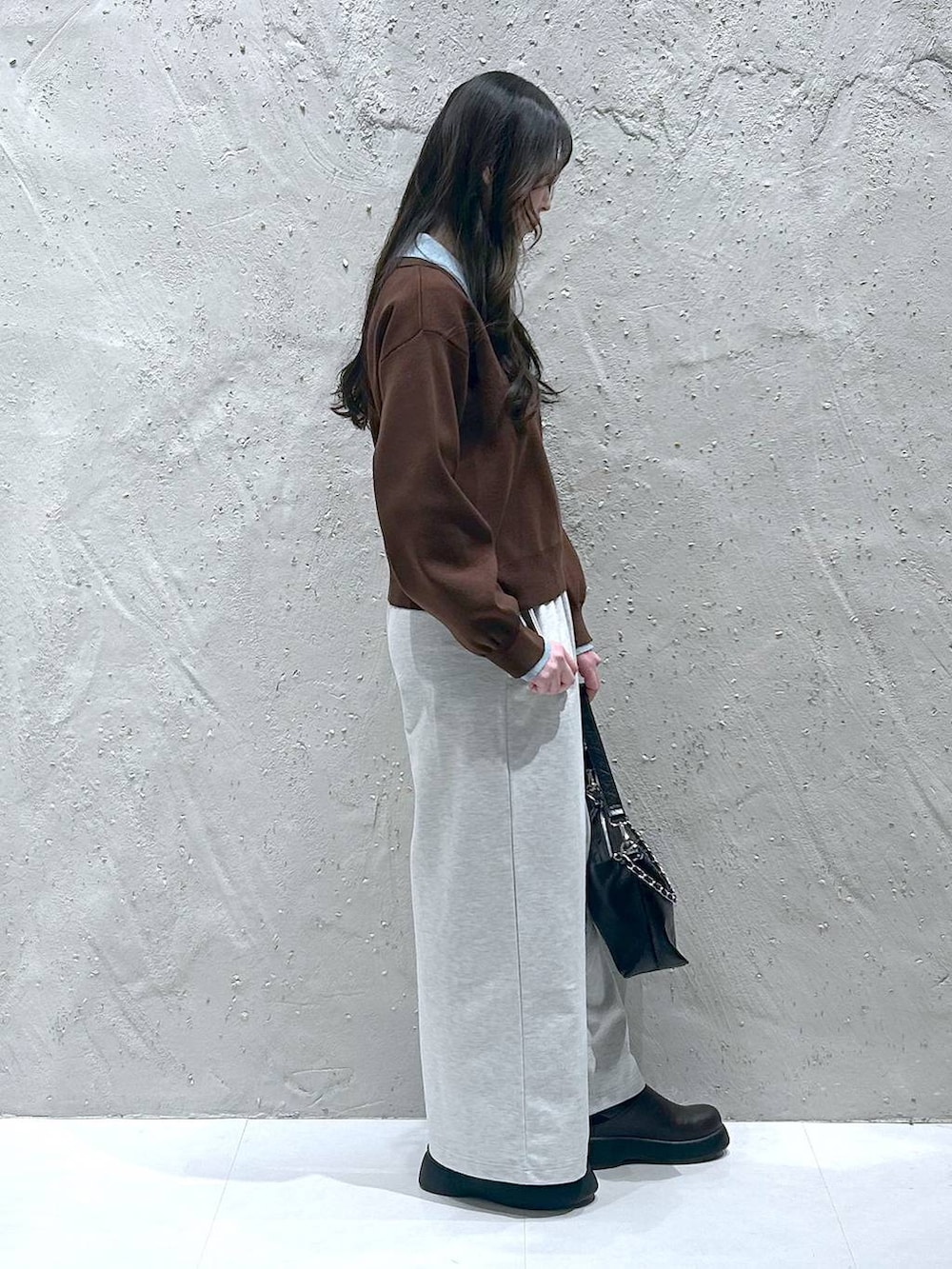 ブラック系のショルダーバッグ、ブラウン系のニット/セーター、ブラウン系のサンダルを着用したレディースの春コーディネートの2枚目の写真