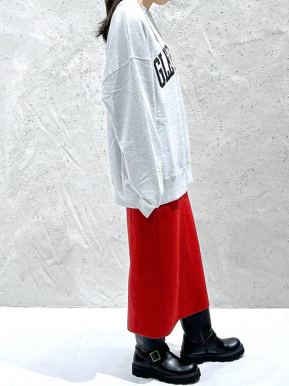 レッド系のスカート、ブラック系のブーツ、グレー系のスウェットを着用したレディースの秋コーディネートの4枚目の写真