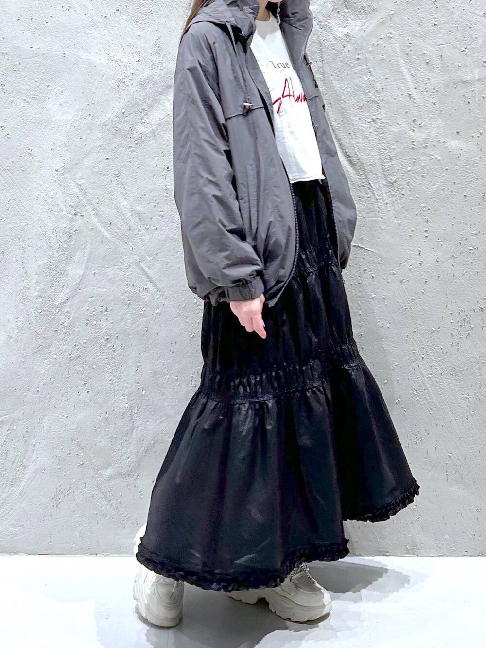 ブラック系のスカート、ホワイト系のスニーカー、ホワイト系のTシャツ/カットソーを着用したレディースの秋コーディネートの4枚目の写真