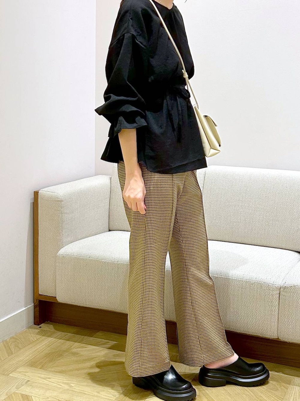 ホワイト系のショルダーバッグ、ホワイト系のサンダル、ブラウン系のスラックスを着用したレディースの秋コーディネートの4枚目の写真