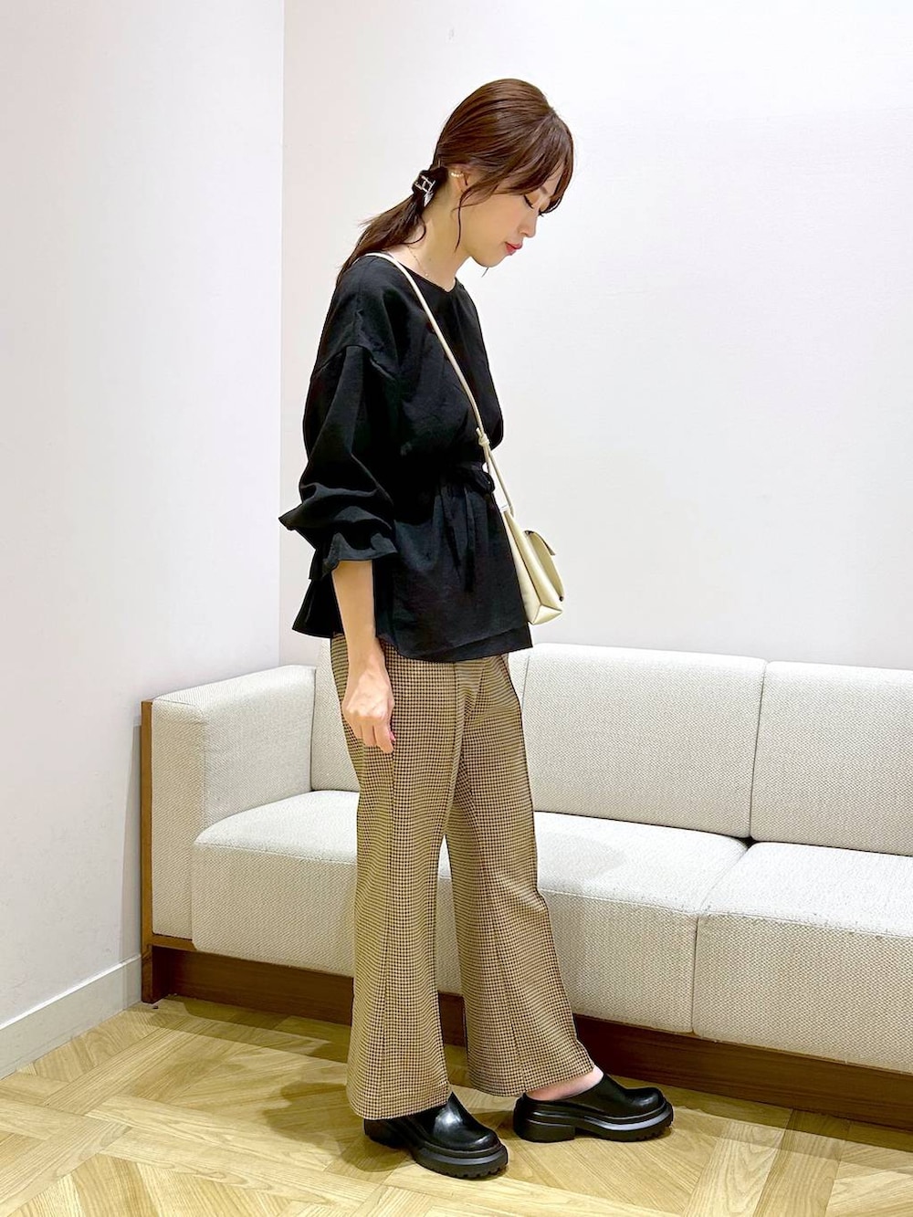 ホワイト系のショルダーバッグ、ホワイト系のサンダル、ブラウン系のスラックスを着用したレディースの秋コーディネートの3枚目の写真