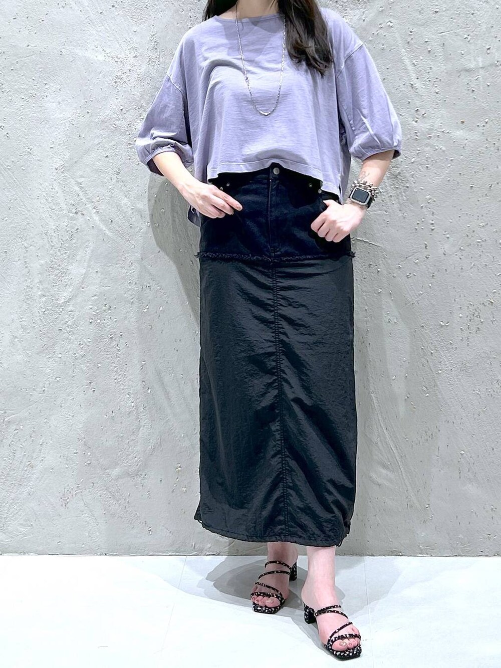 ブラック系のデニムスカート、ブラック系のサンダル、パープル系のTシャツ/カットソーを着用したレディースの夏コーディネートの2枚目の写真