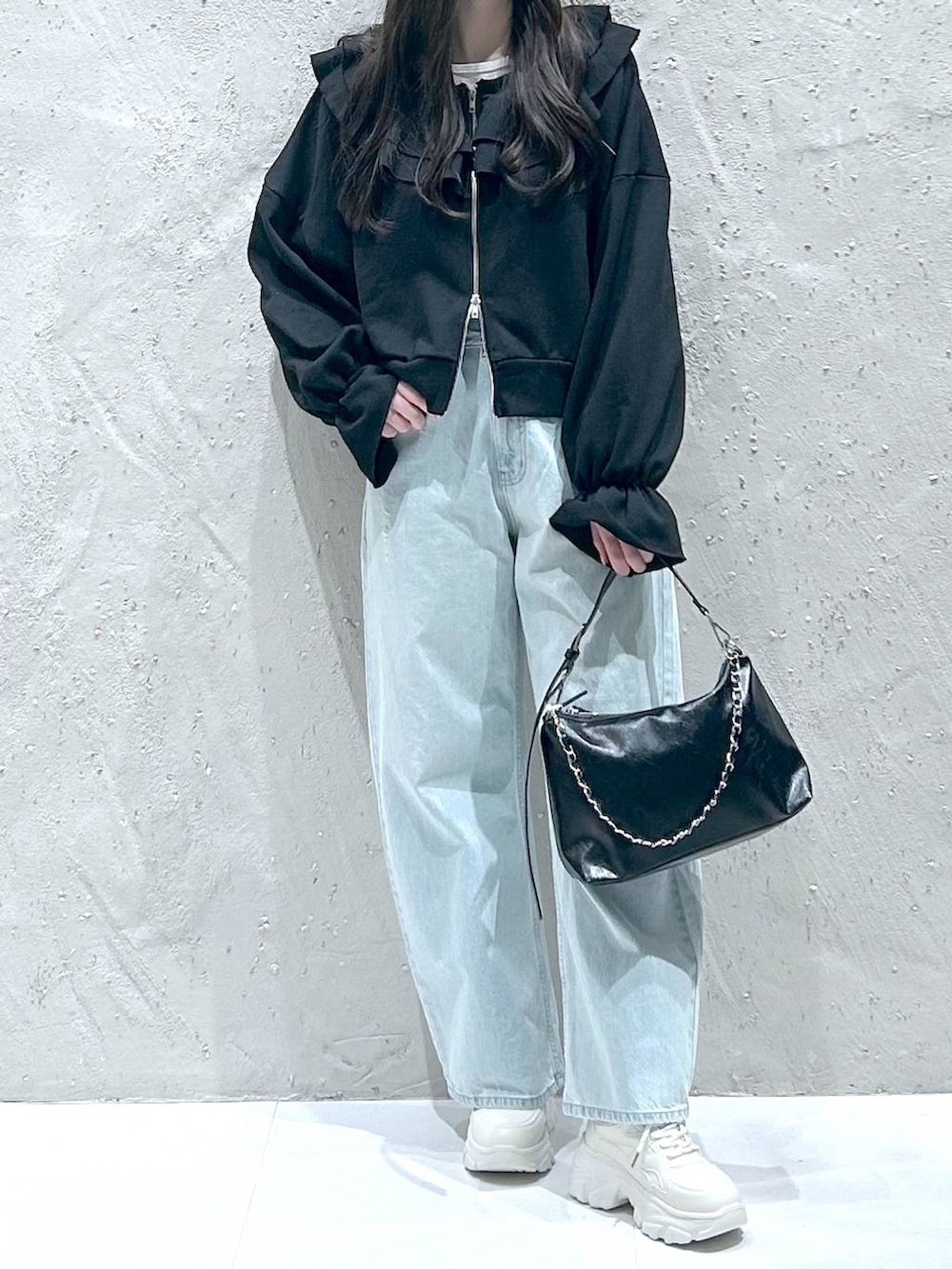 ブルー系のデニムパンツ、ブラック系のショルダーバッグ、ブラック系のスウェットを着用したレディースの冬コーディネートの3枚目の写真