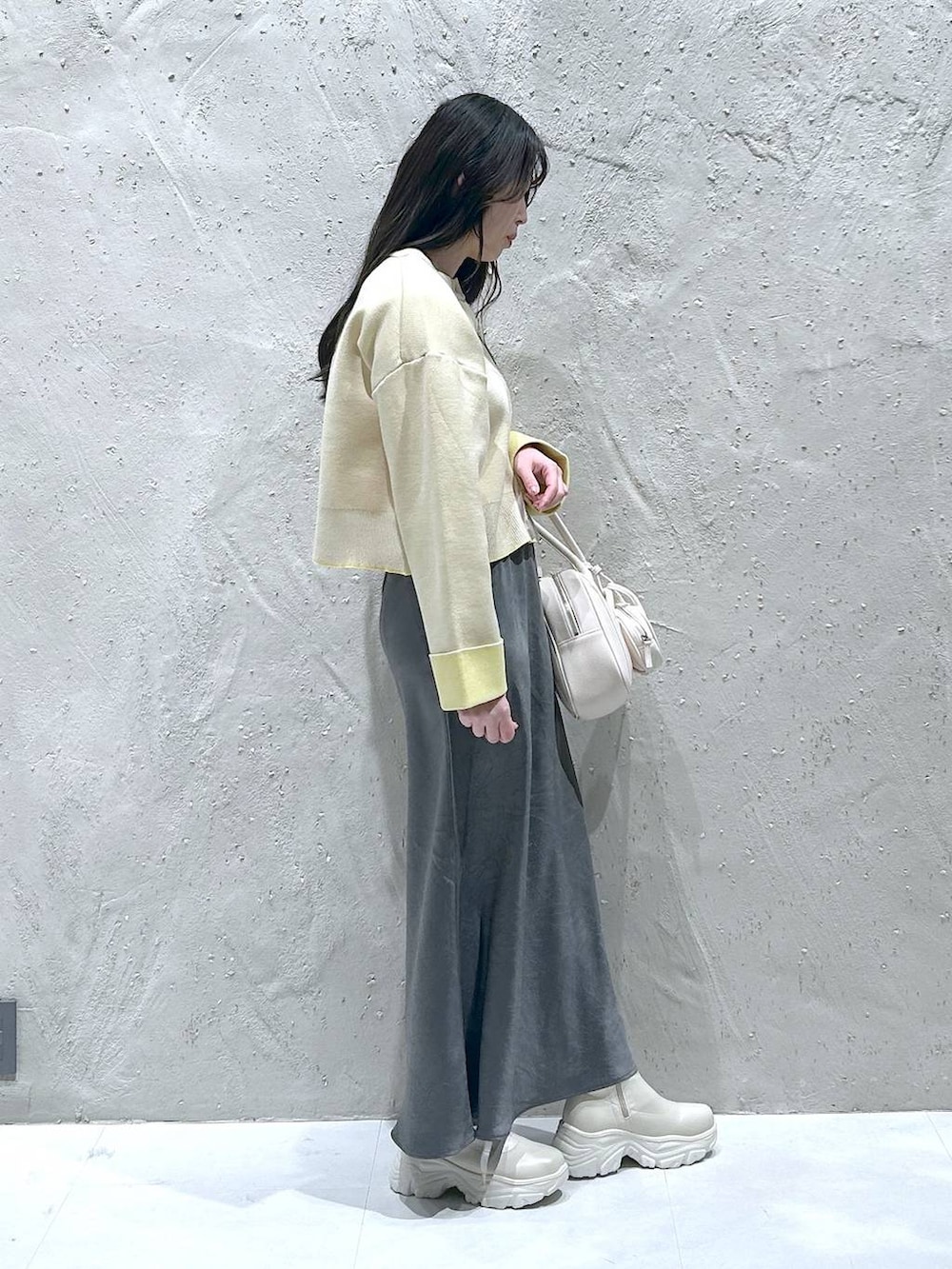 ホワイト系のブーツ、グレー系のスカート、ホワイト系のボストンバッグを着用したレディースの冬コーディネートの2枚目の写真