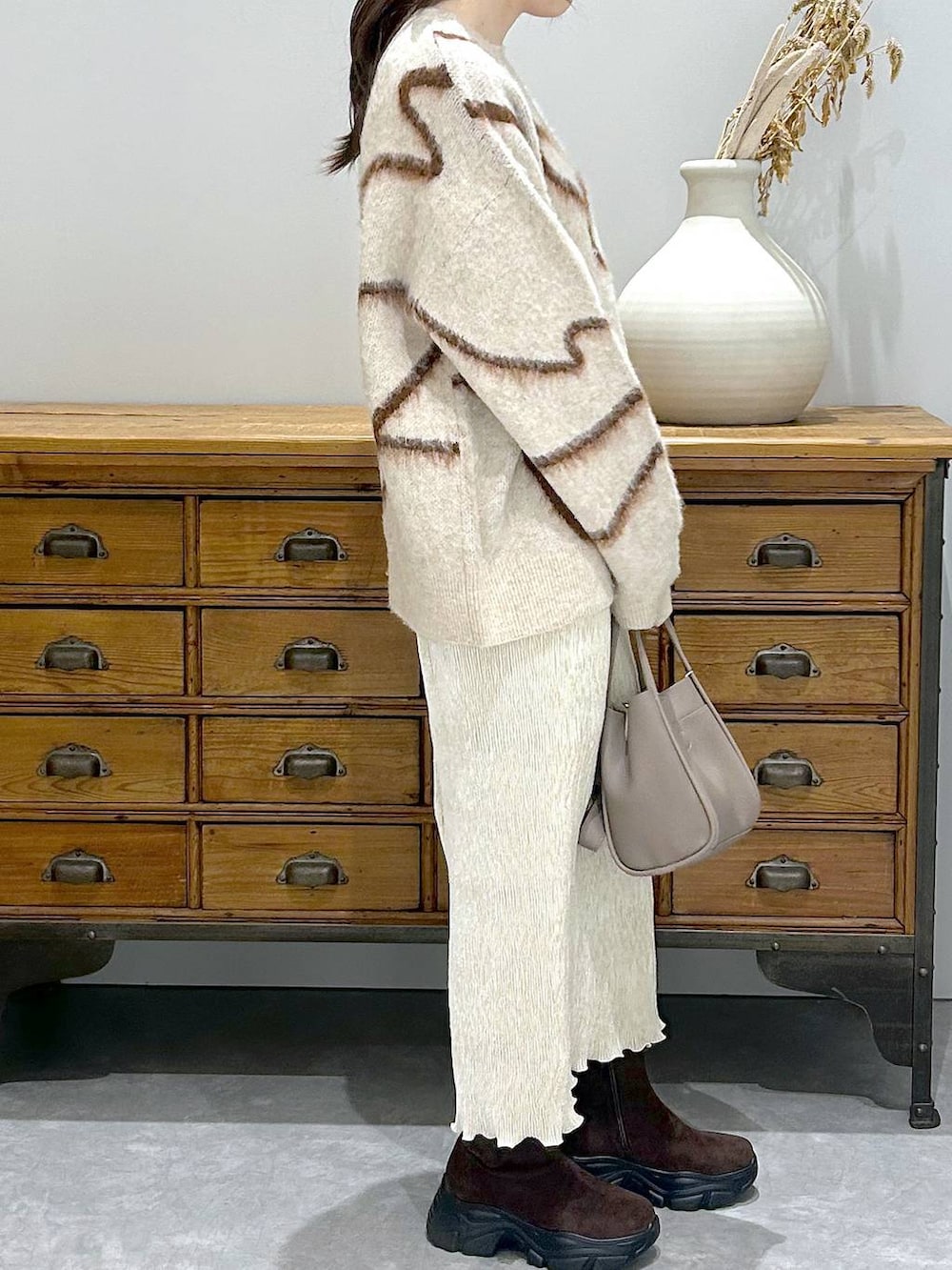 ブラウン系のブーツ、グレー系のショルダーバッグ、ホワイト系のスカートを着用したレディースの秋コーディネートの5枚目の写真