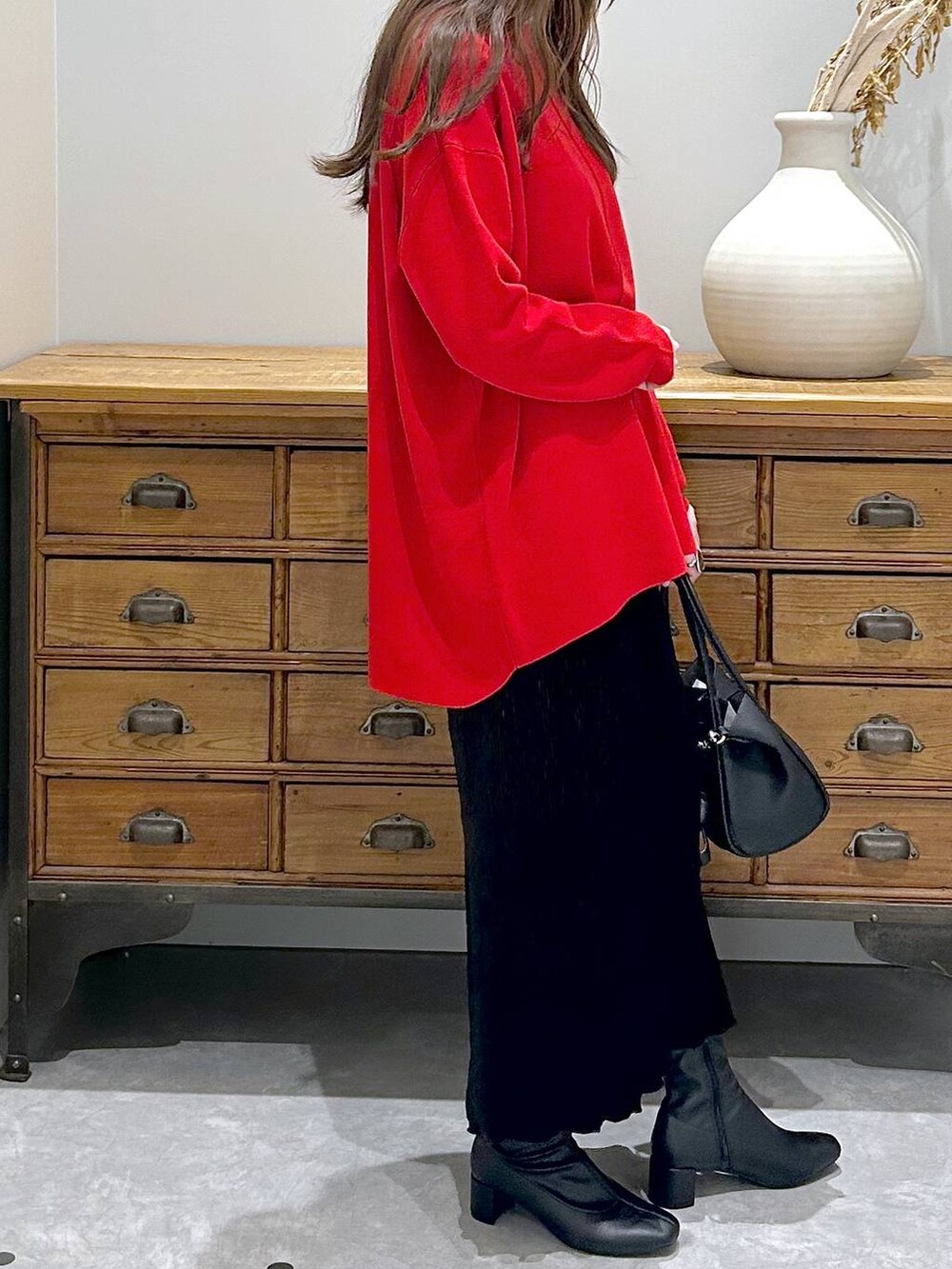 ブラック系のショルダーバッグ、ブラック系のスカート、ブラック系のブーツを着用したレディースの秋コーディネートの4枚目の写真