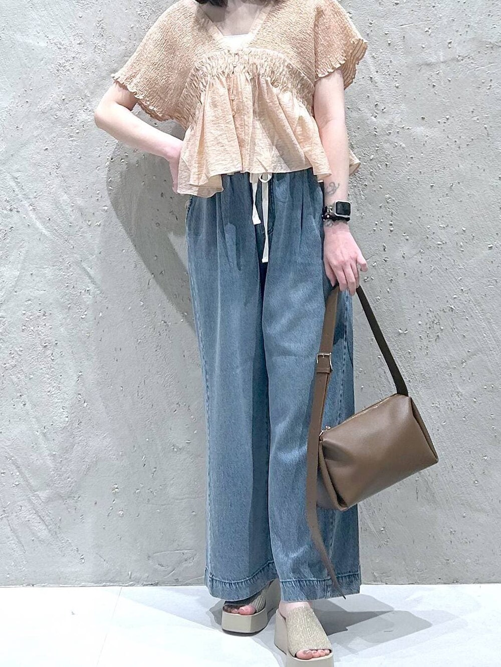 ブルー系のデニムパンツ、ホワイト系のサンダル、ブラウン系のショルダーバッグを着用したレディースの夏コーディネートの3枚目の写真