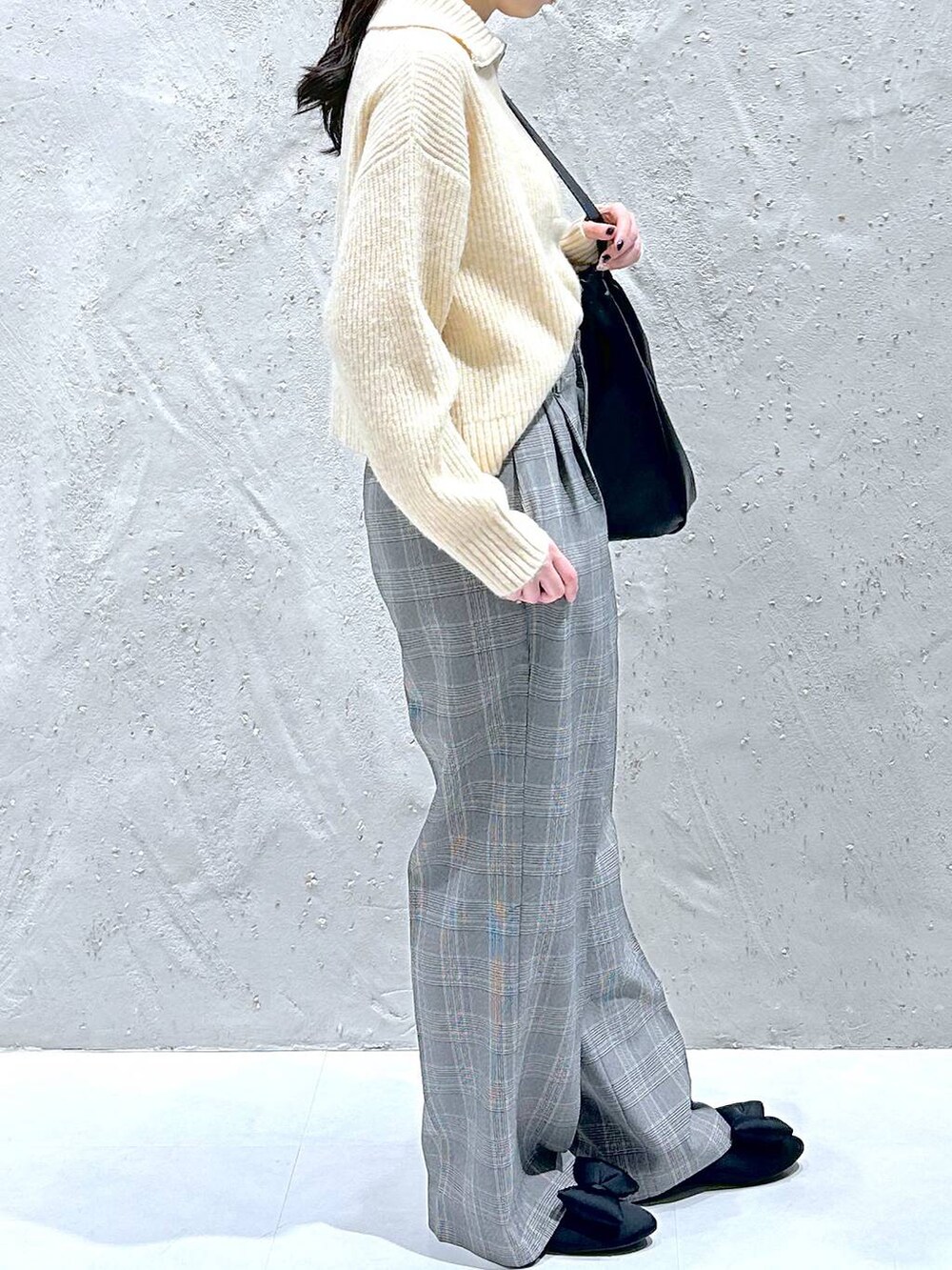 ブラック系のショルダーバッグ、グレー系のスラックス、ホワイト系のニット/セーターを着用したレディースの冬コーディネートの3枚目の写真