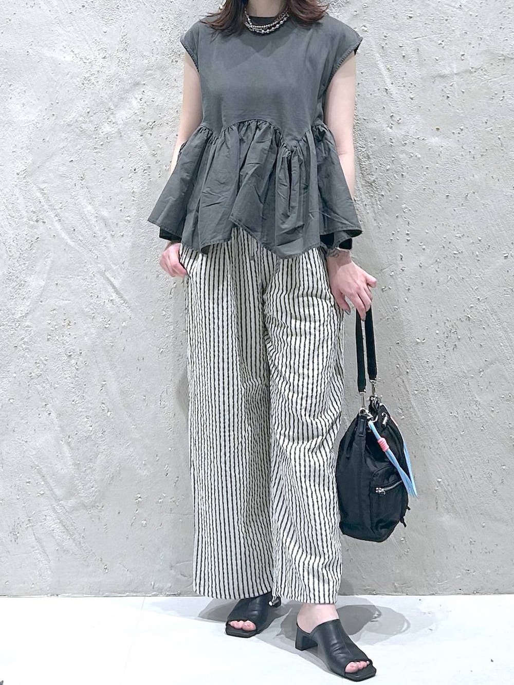 グレー系のTシャツ/カットソー、ブラック系のサンダル、ブラック系のショルダーバッグを着用したレディースの秋コーディネートの3枚目の写真