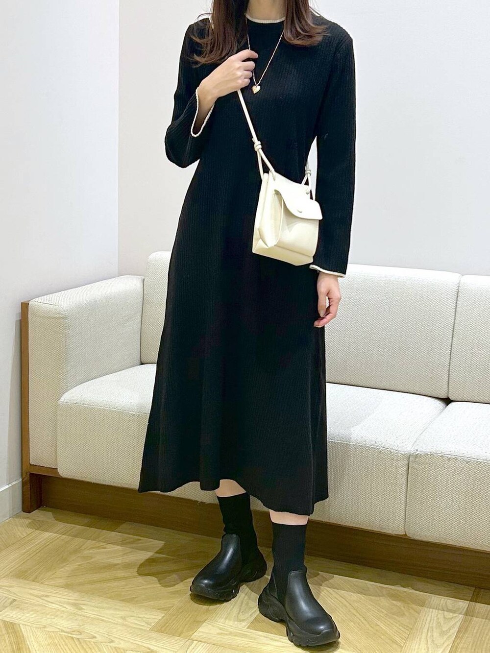 ホワイト系のショルダーバッグ、ブラック系のワンピース、ブラック系のブーツを着用したレディースの秋コーディネートの4枚目の写真