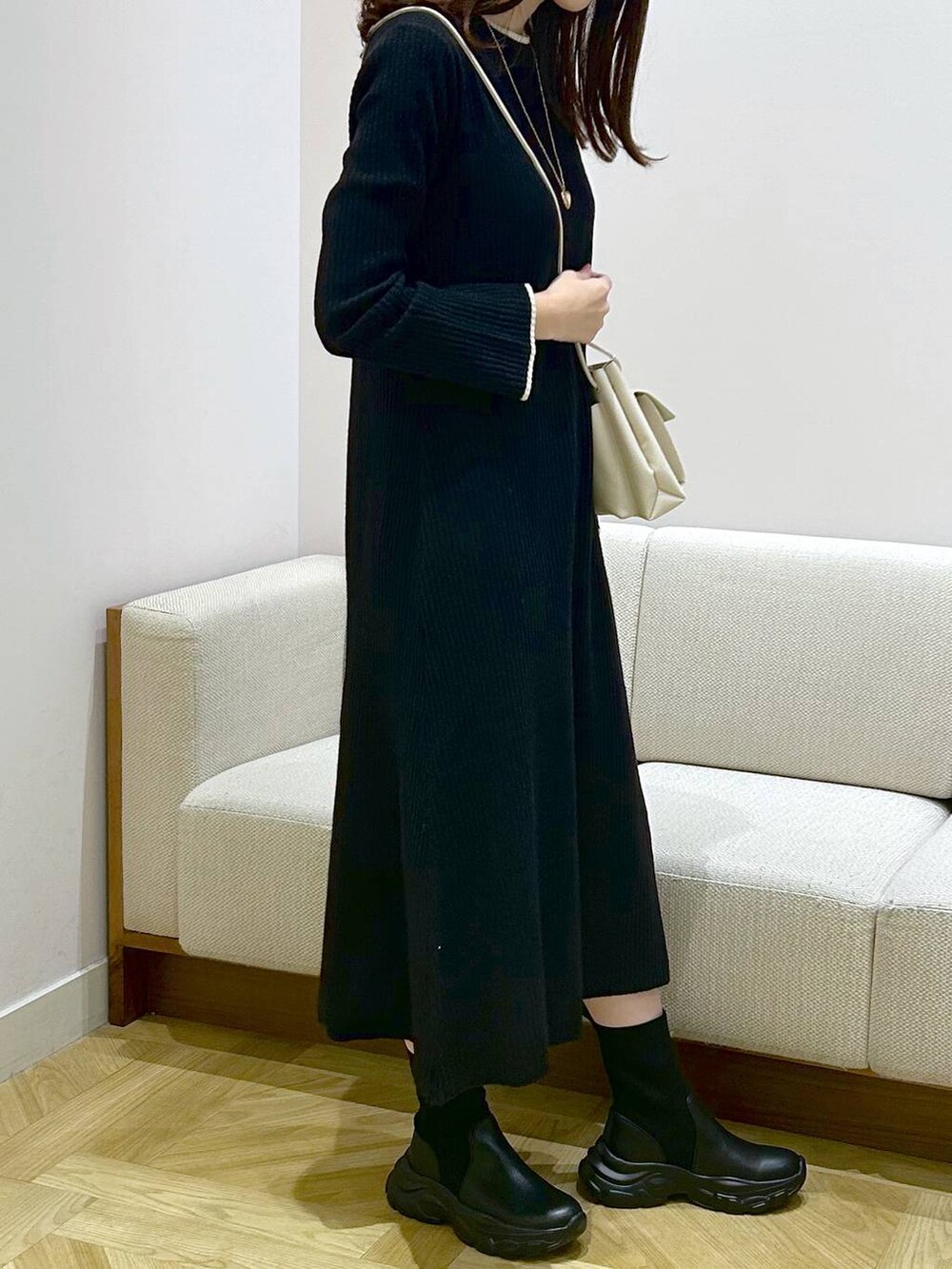 ホワイト系のショルダーバッグ、ブラック系のワンピース、ブラック系のブーツを着用したレディースの秋コーディネートの2枚目の写真