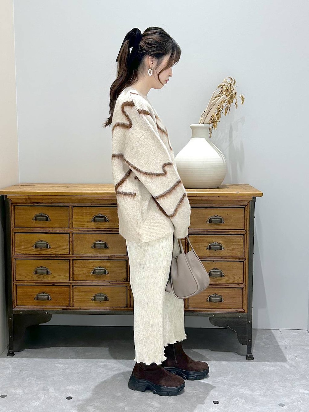 ブラウン系のブーツ、グレー系のショルダーバッグ、ホワイト系のスカートを着用したレディースの秋コーディネートの2枚目の写真