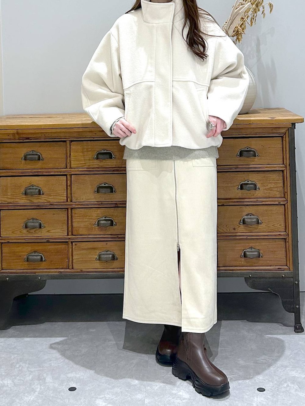 ブラウン系のブーツ、ホワイト系のスカート、ホワイト系のブルゾンを着用したレディースの冬コーディネートの2枚目の写真