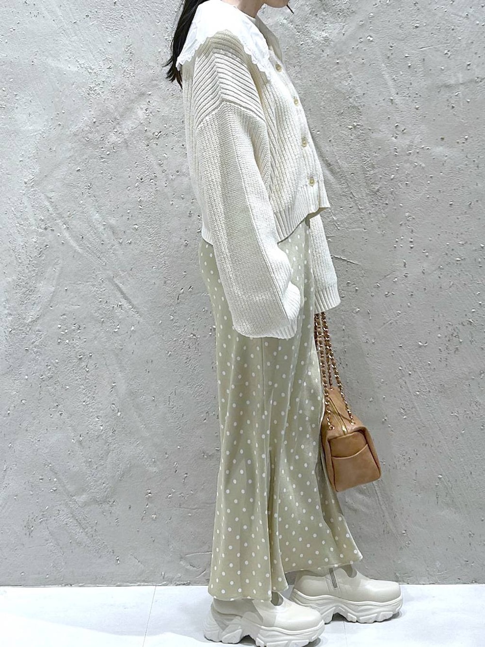 ホワイト系のブーツ、ベージュ系のスカート、ブラック系のショルダーバッグを着用したレディースの冬コーディネートの4枚目の写真