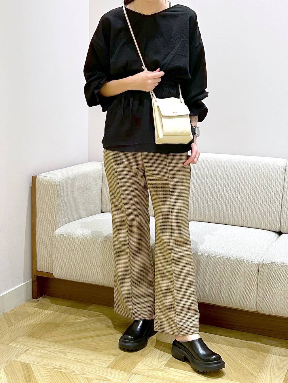 ホワイト系のショルダーバッグ、ホワイト系のサンダル、ブラウン系のスラックスを着用したレディースの秋コーディネートの2枚目の写真