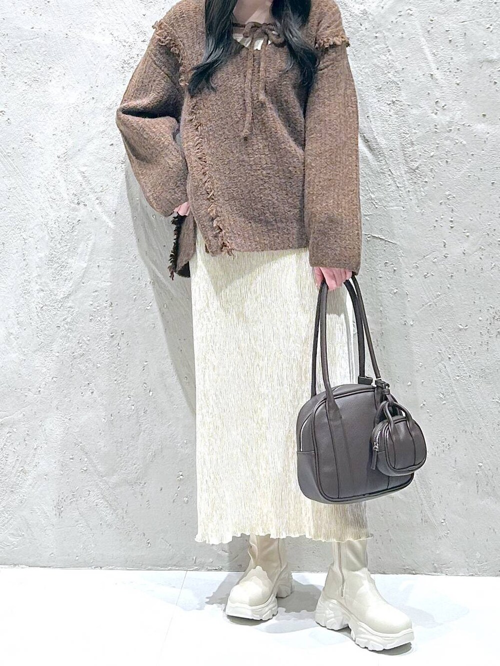 ブラウン系のニット/セーター、ホワイト系のブーツ、ホワイト系のスカートを着用したレディースの冬コーディネートの3枚目の写真