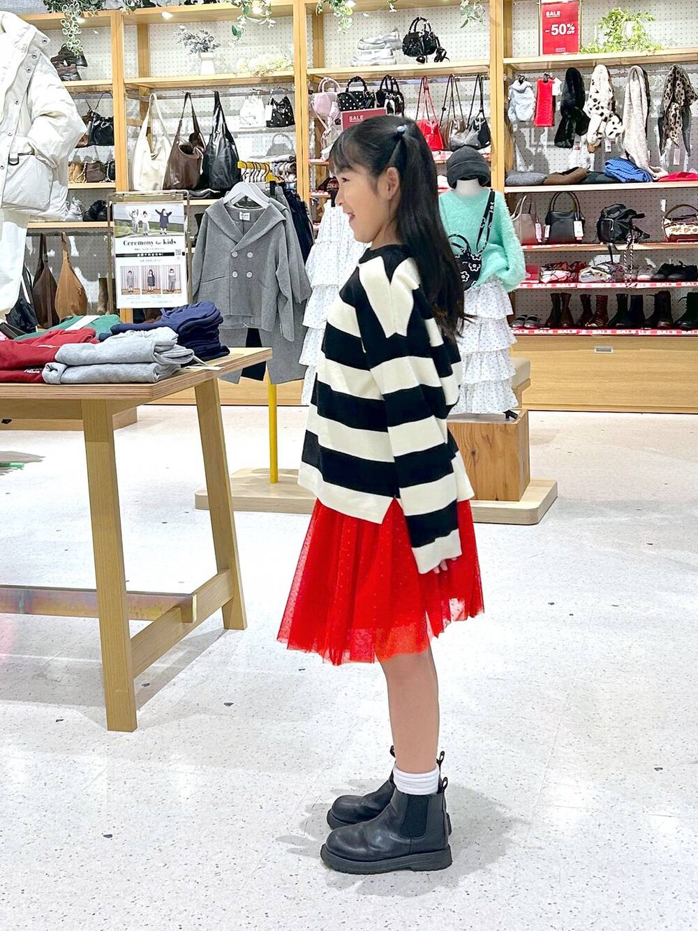 ホワイト系のニット/セーター、レッド系のスカートを着用したキッズの冬コーディネートの2枚目の写真