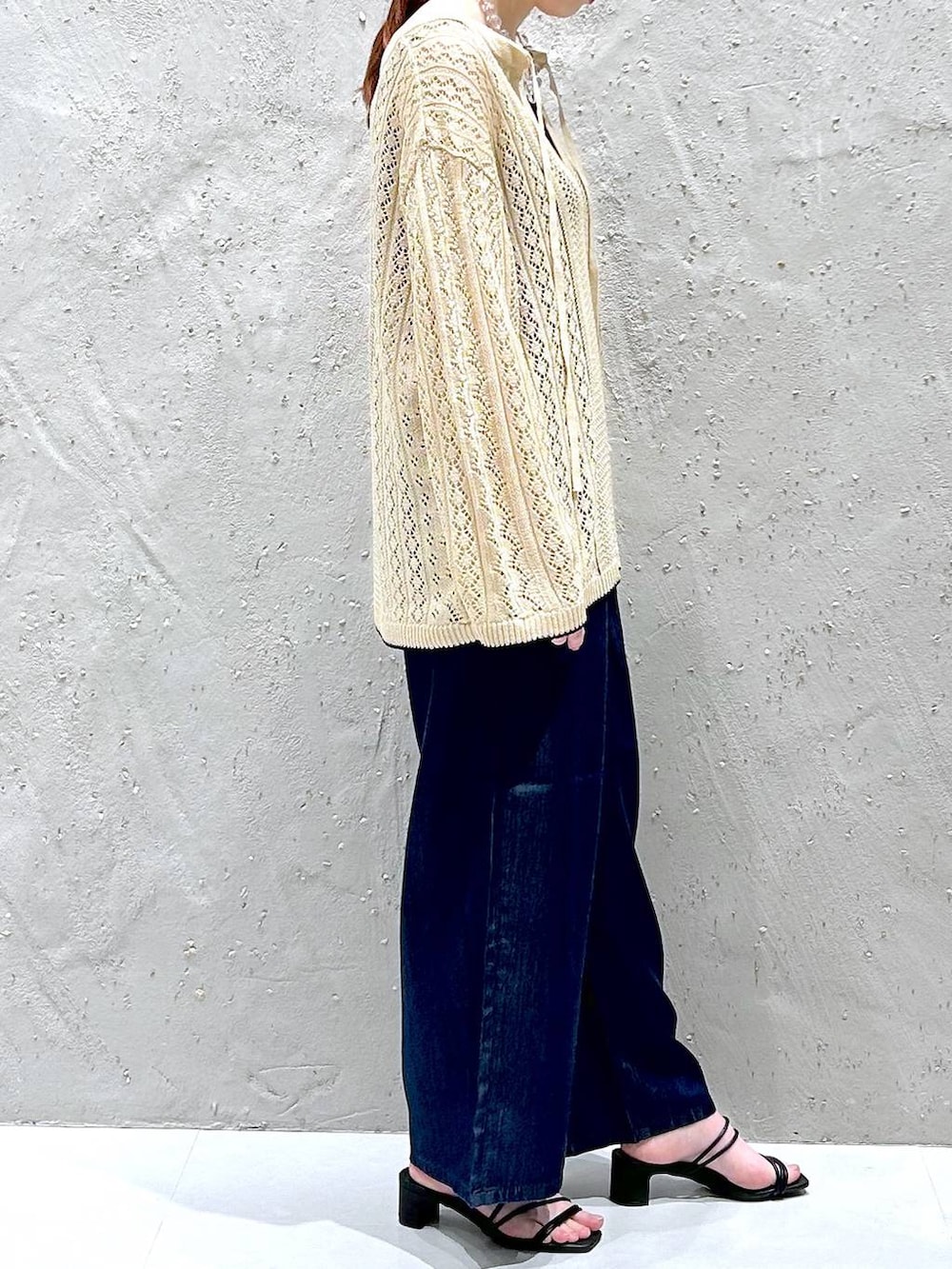 ホワイト系のニット/セーター、ブルー系のデニムパンツ、ブラック系のタンクトップを着用したレディースの春コーディネートの4枚目の写真