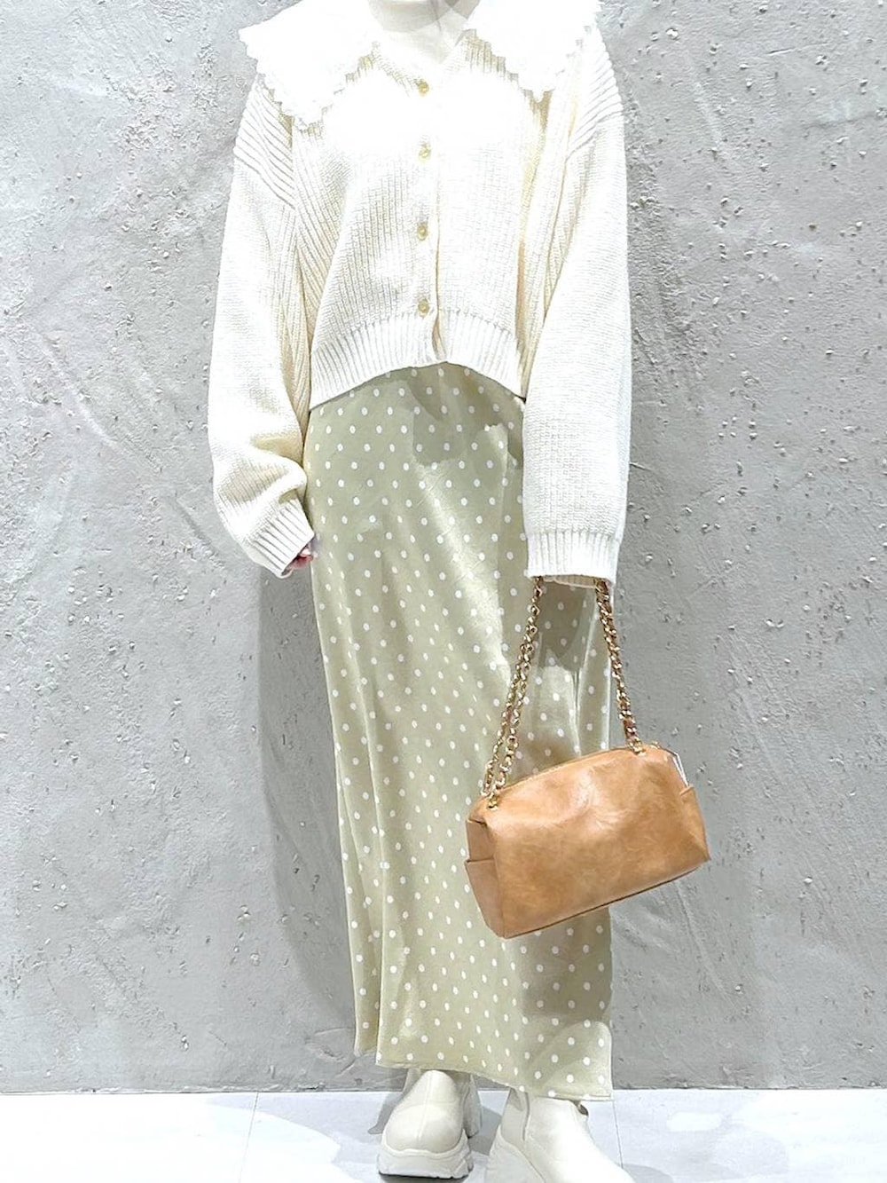 ホワイト系のブーツ、ベージュ系のスカート、ブラック系のショルダーバッグを着用したレディースの冬コーディネートの3枚目の写真