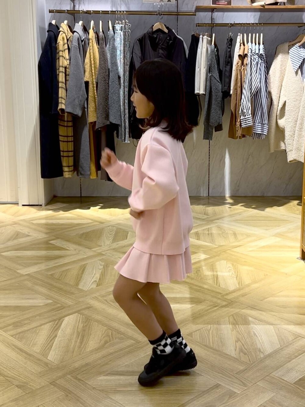 ブラック系のスニーカー、ピンク系のスカート、ピンク系のニット/セーターを着用したキッズの冬コーディネートの2枚目の写真