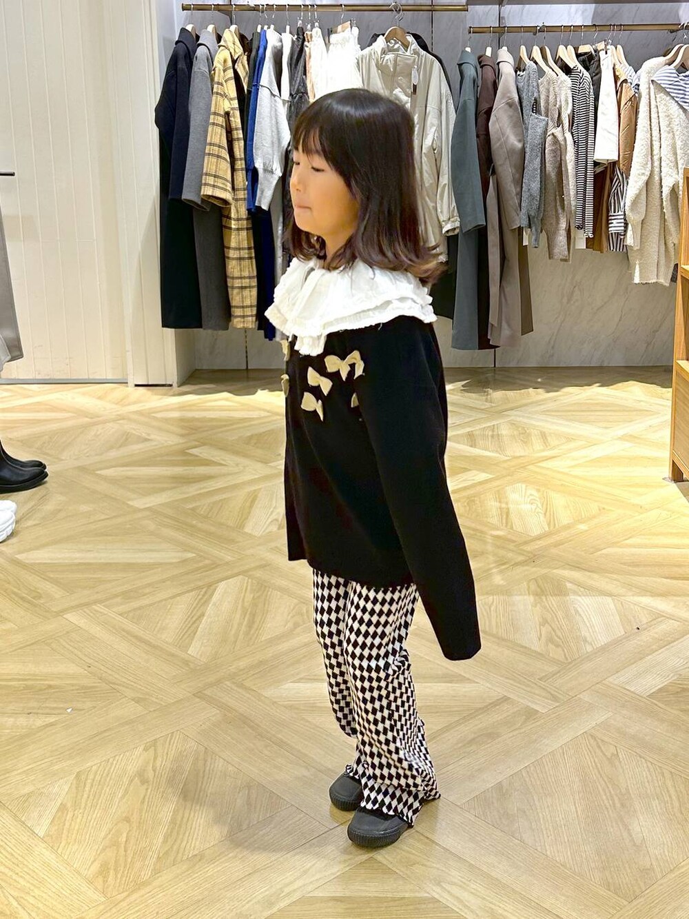 ホワイト系のシャツ/ブラウス、ブラック系のニット/セーターを着用したレディースの冬コーディネートの2枚目の写真