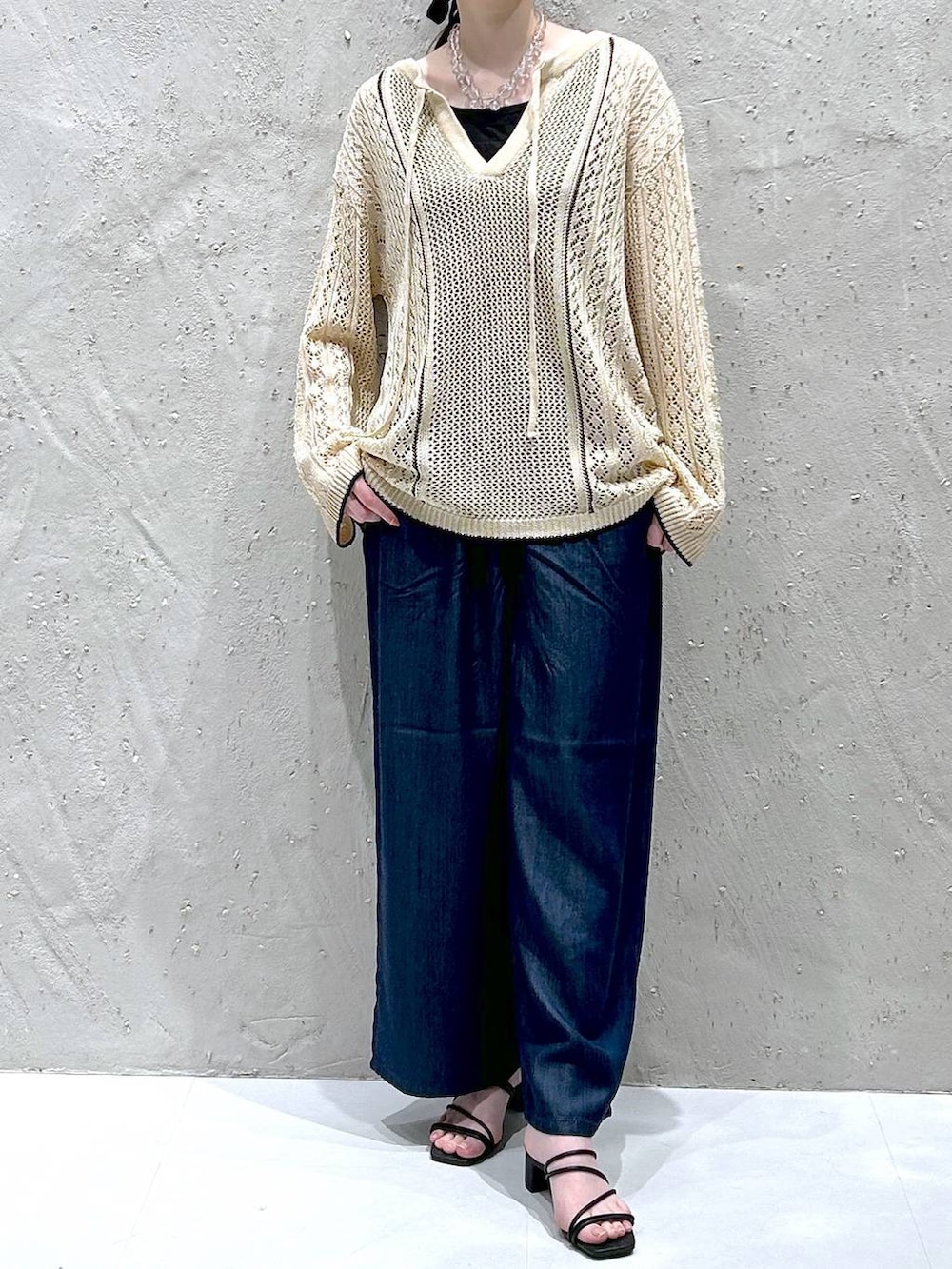 ホワイト系のニット/セーター、ブルー系のデニムパンツ、ブラック系のタンクトップを着用したレディースの春コーディネートの2枚目の写真