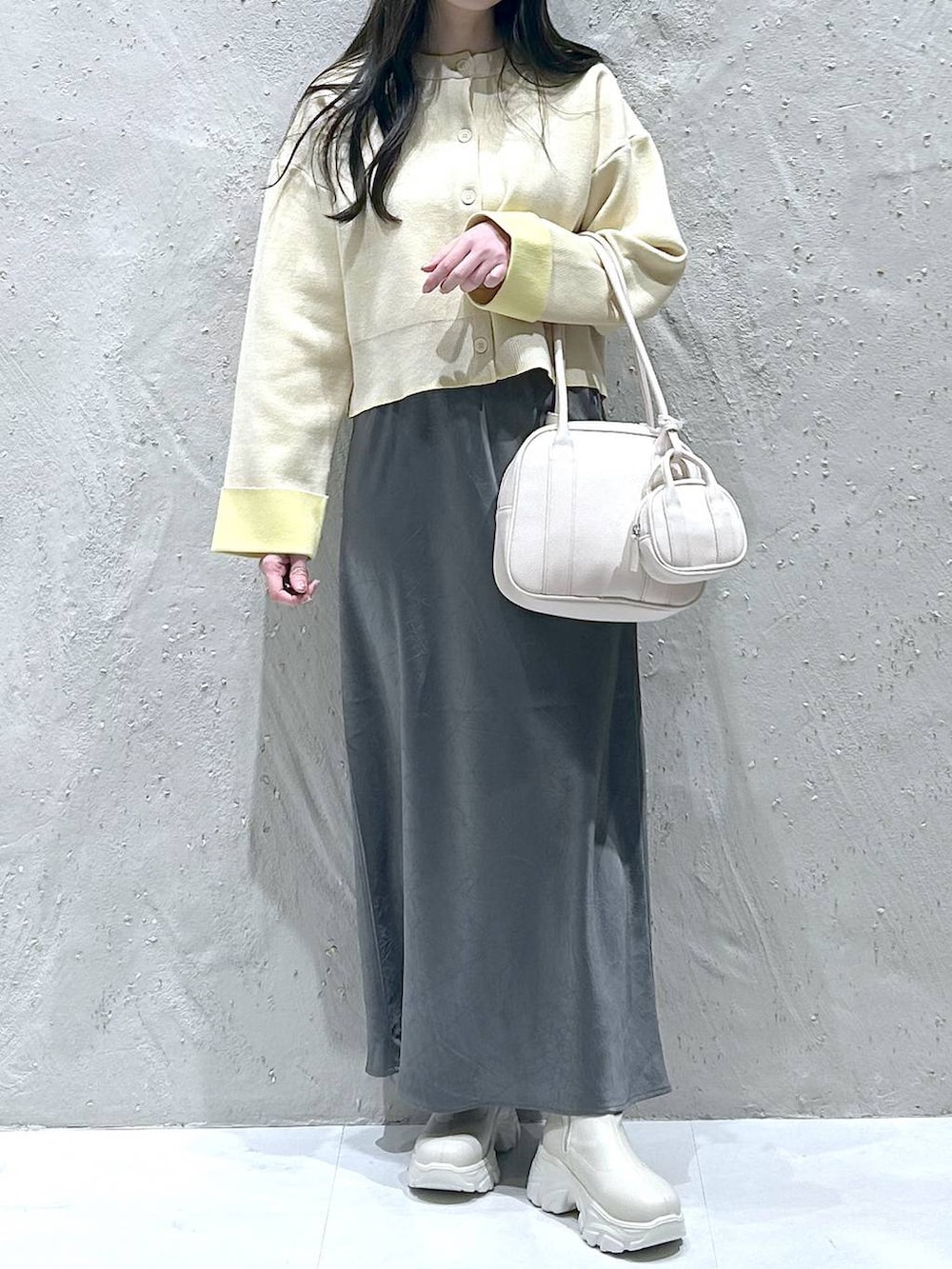 ホワイト系のブーツ、グレー系のスカート、ホワイト系のボストンバッグを着用したレディースの冬コーディネートの3枚目の写真