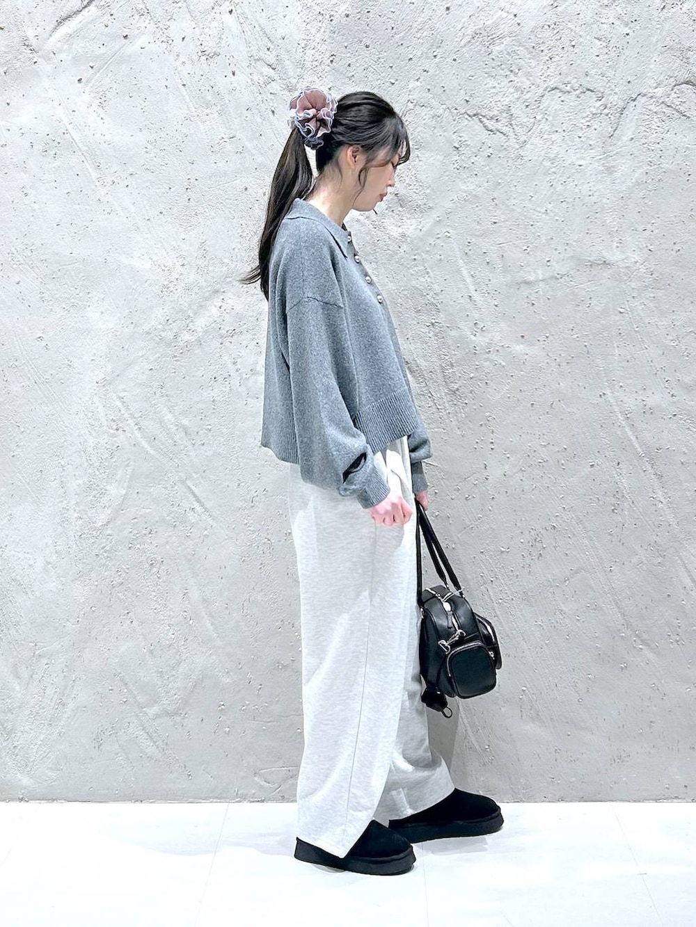 グレー系のスウェットパンツ、ブラック系のブーツ、ブラック系のボストンバッグを着用したレディースの冬コーディネートの2枚目の写真